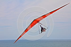 Hang gliding man on an orange wing in the sky
