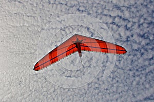 Hang gliding man on an orange wing in the sky