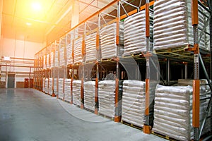 Hangar warehouse with rows of shelves with white polyethylene bags with finished factory production