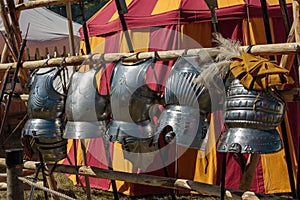 Hanged Metallic Armors in Line in front of Red and Yellow Tent
