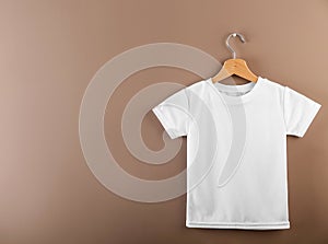 Hanger with blank white t-shirt on color background