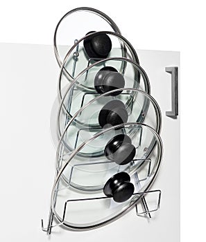 A hanger with glass lids for cooking pots hung on the door of a