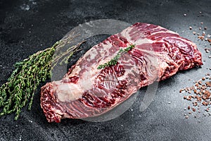 Hanger or onglet raw beef meat steak on butcher table with herbs. Black background. Top View