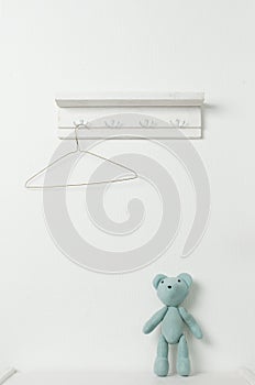 Hanger with shoulders and a teddy bear on a white wall background