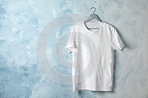 Hanger with white t-shirt on color background