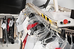 Hangers with clothes on conveyor at dry-cleaner`s