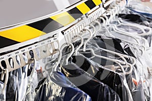 Hangers with clothes on garment conveyor at dry-cleaner`s