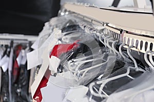 Hangers with clothes on garment conveyor at dry-cleaner`s, closeup
