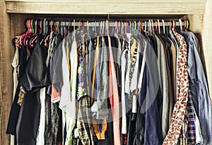 Hangers with different clothes in wardrobe closet