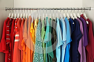 Hangers with different colorful clothes on rack