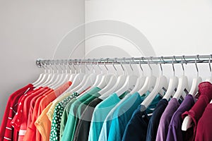 Hangers with different colorful clothes on rack