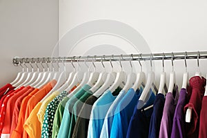 Hangers with different colorful clothes on rack