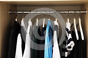 Hangers with teenage clothes on rack in wardrobe