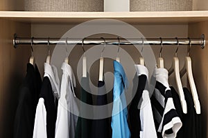 Hangers with teenage clothes on rack in wardrobe