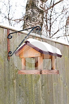 Hanging bird feeder covered by snow in winter.