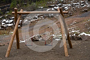 Hanging children swing on wooden poles in the national park.