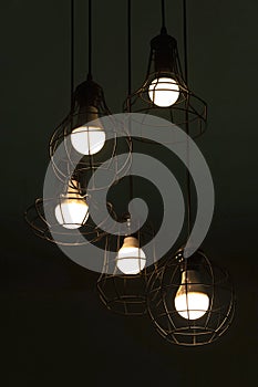 Hanging classic black metal light bulb in the dark night interior background