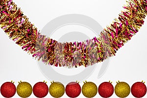 Hanging colorful tinsel with red and gold Christmas baubles, isolated on a white background with copy space, christmas decorations