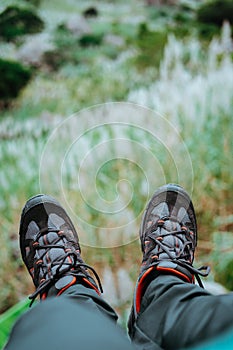 Hanging feet with trekking footwear over hill with sugarcane plants. Santo Antao Island, Cape Verde