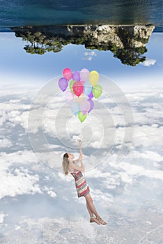 Hanging girl to a group of balloons flying toward a world upside