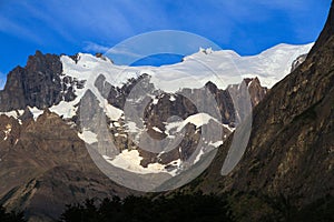 A hanging Glacier, peeking out over the forest, at the top of one of the mountains of the French Valley in Torres Del Paine Natio