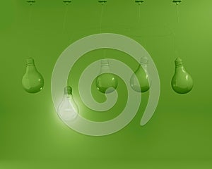 Hanging green light bulbs with glowing one different idea on pastel green background. Minimal concept. top view.
