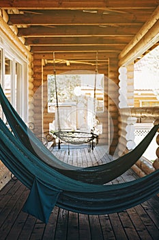 Hanging hammocks for relaxing on the open terrace of a wooden house. Country rest and relaxation in nature in summer time. Copy