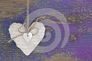 Hanging heart and purple wooden background in country style.