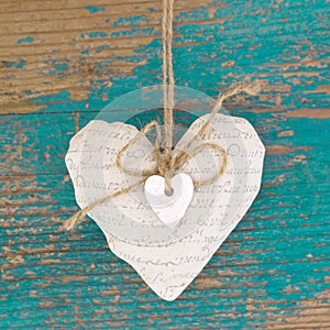 Hanging heart and turquoise wooden background in country style.