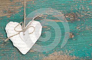 Hanging heart and turquoise wooden background in country style.