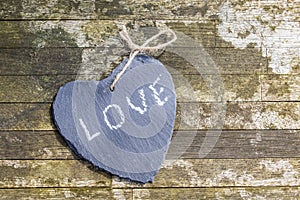 Hanging heart and wooden background in country style.