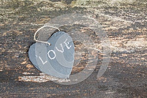 Hanging heart and wooden background in country style.