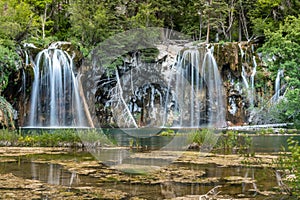 Hanging Lake waterfall in Colorado with trees and green water