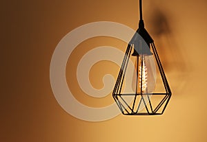 Hanging lamp bulb in chandelier against yellow background