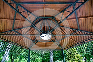 Hanging lamp on the ceiling of the gazebo with an iron frame.