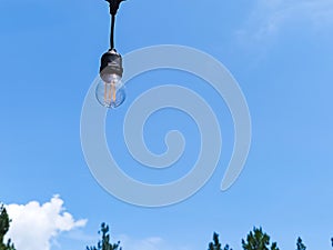 Hanging light bulb against clear blue sky