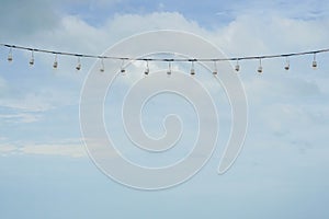 Hanging light bulbs wire with blue sky backdrop