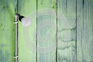 Hanging modern light bulb with green wooden planks background