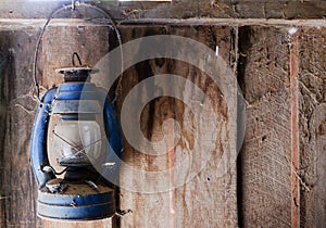 Hanging old lantern with cobweb on wooden wall.