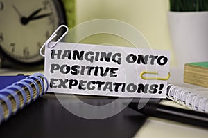 Hanging Onto Positive Expectation on the paper isolated on it desk. Business and inspiration concept