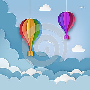 Hanging paper craft hot air balloons, flying birds, clouds on the daytime sky background. Cloudy sky background.