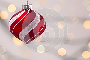 Hanging Red and White Christmas Ornament with a Bright Lights in the Background