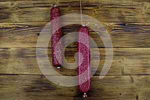 Hanging salami sausages on wooden background