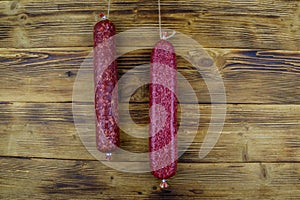 Hanging salami sausages on wooden background