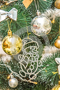 Hanging snowman decoration on the Christmas tree. Gold and silver baubles, multi-colored bows, animals, bells, lit garlands