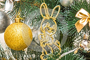 Hanging squirrel figure decoration on the Christmas tree. Gold and silver baubles, multi-colored bows, bells, lit garlands against