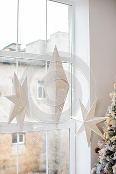 Hanging star lantern lights during holiday winter season. Decoration White Christmas stars in window. Advent time. A lamp in shape