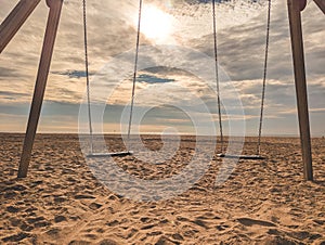 Hanging swings in sandy beach in sunny daylight