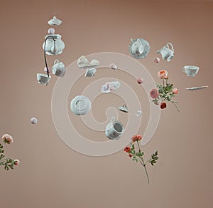 Hanging tableware on brown background. Teapot, teacups, and flowers.