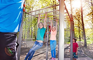 Hanging teens on horizontal bar at sports ground